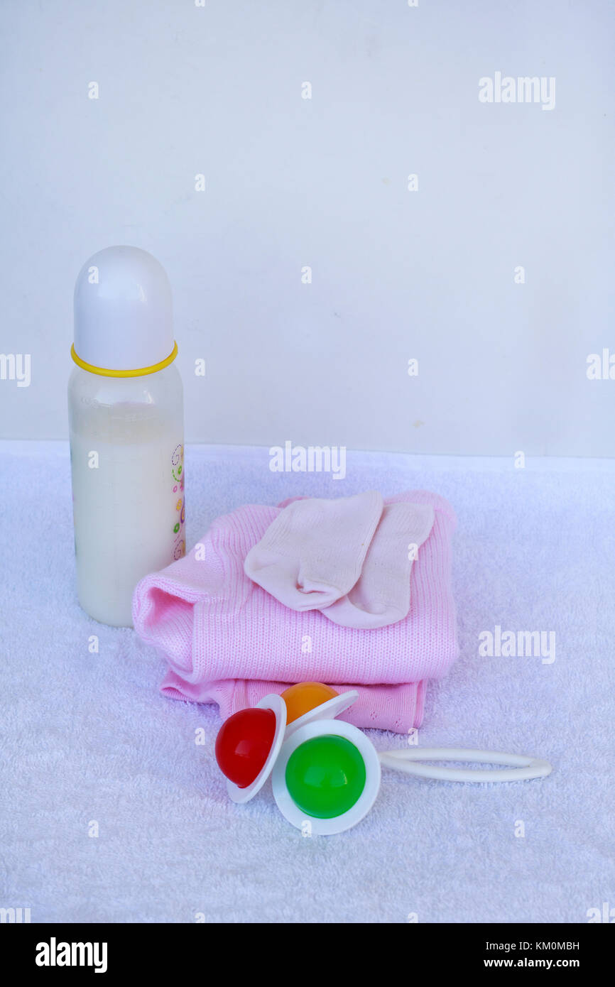Impostare per la ragazza neonata con latte per neonati, giocattolo, il succhietto, anti graffio protezione mano guanti e calze su sfondo bianco. Foto Stock