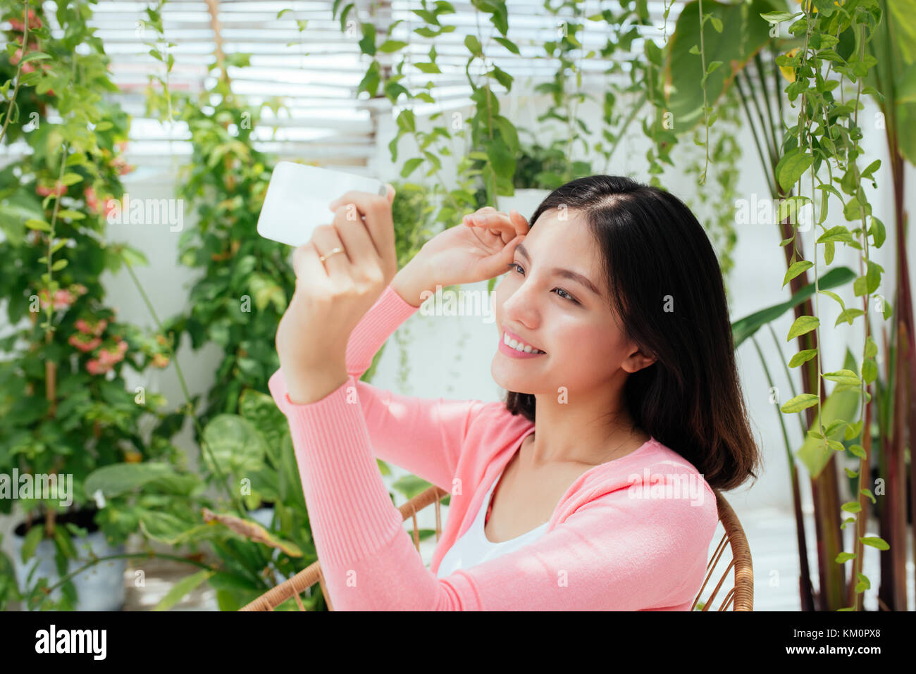 Carino ragazza asiatica sta prendendo selfie foto e seduti in giardino soleggiato. Foto Stock