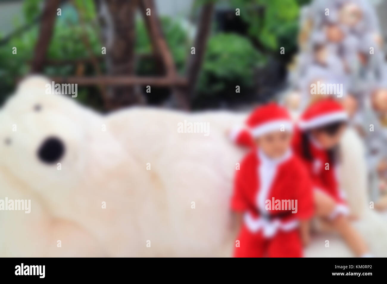 Out of Focus and Blurred Image for background of Little Boy and Girl in cute Santa abiti che giocano con un Big Polar Bear Toy Foto Stock