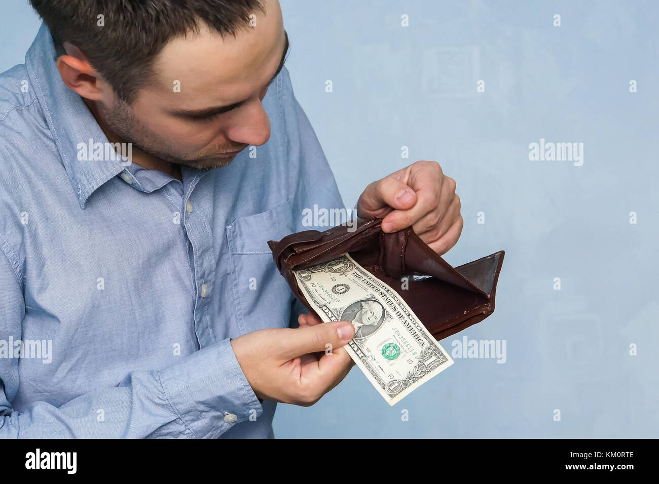 L'uomo ottiene denaro dal portafogli. mani close-up tenendo un dollaro e un portafoglio in pelle. la povertà e la disoccupazione. Foto Stock