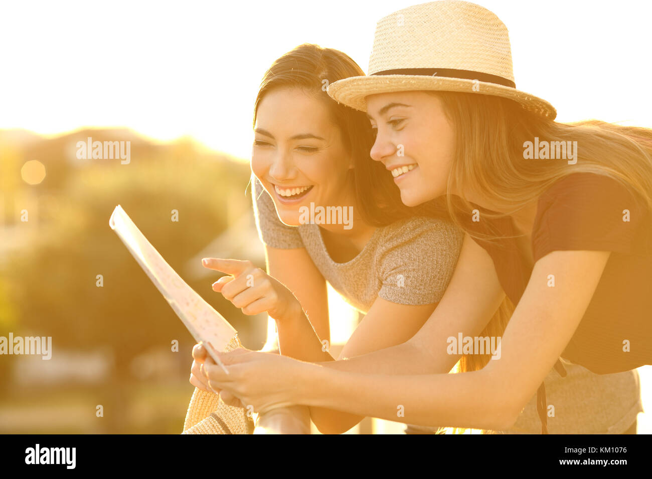 Due turisti divertente la lettura di una mappa su carta in un hotel con balcone sulla vacanze al tramonto Foto Stock