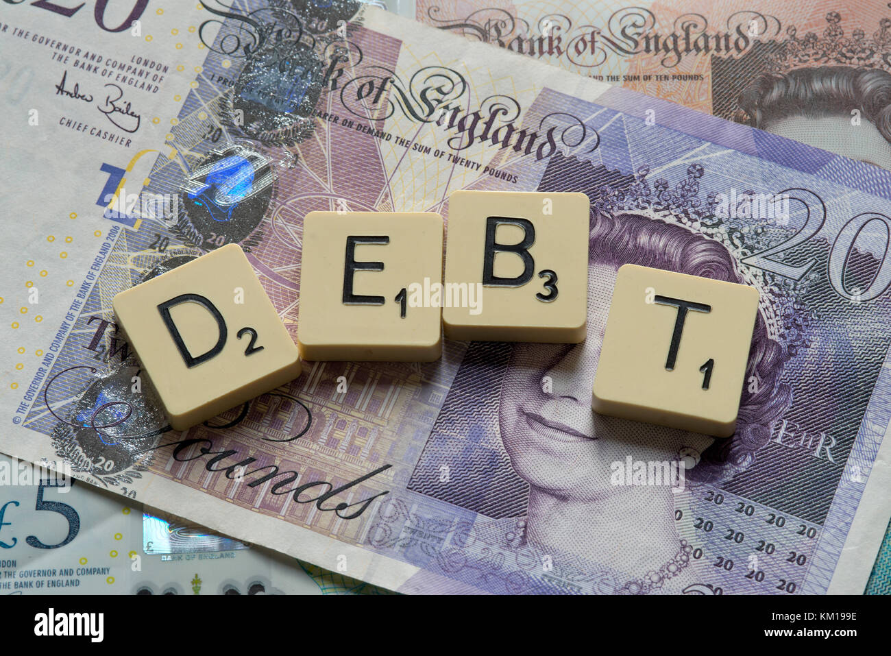 Lettere di scrabble debito controllo ortografico con nuove sterline inglesi (GBP) £20, £10, £5 note e la nuova British pound monete. Foto Stock