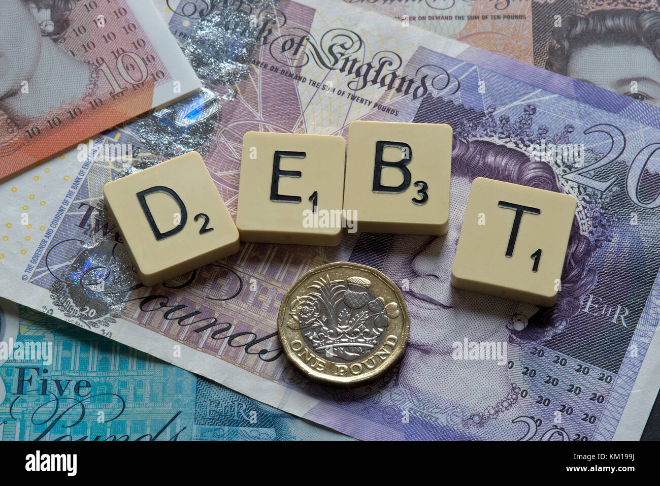 Lettere di scrabble debito controllo ortografico con nuove sterline inglesi (GBP) £20, £10, £5 note e la nuova British pound monete. Foto Stock