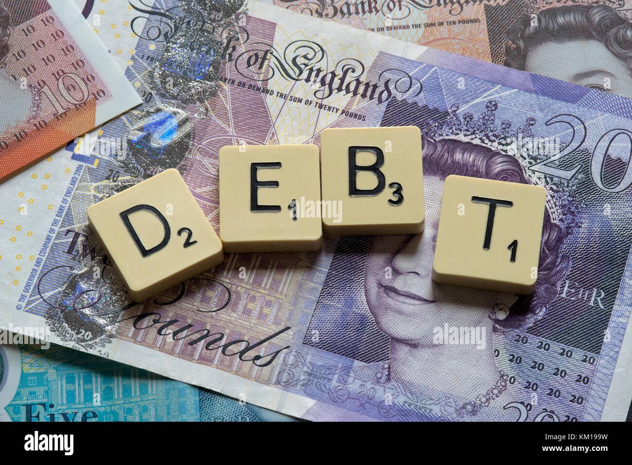 Lettere di scrabble debito controllo ortografico con nuove sterline inglesi (GBP) £20, £10, £5 note e la nuova British pound monete. Foto Stock