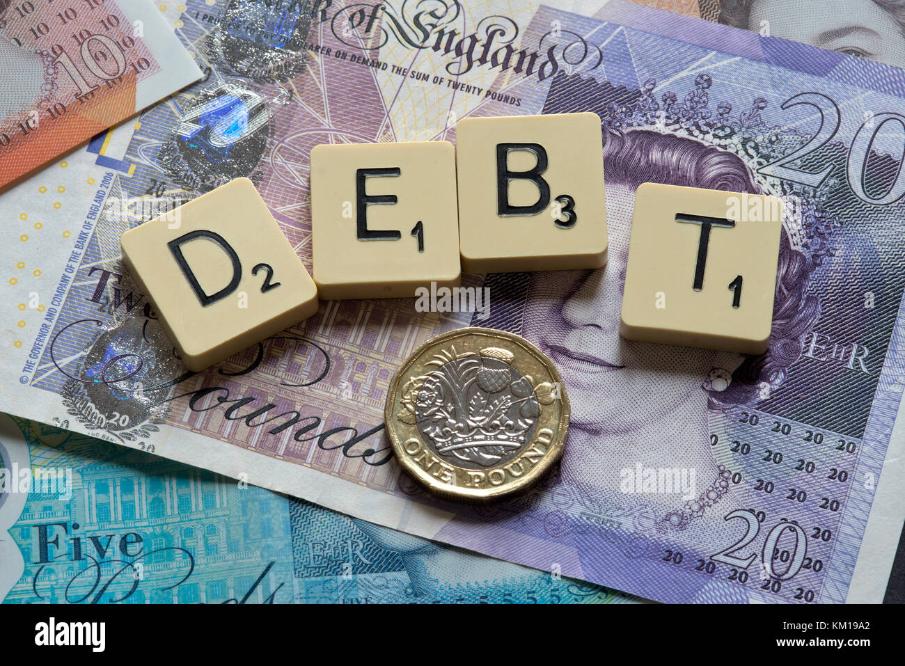 Lettere di scrabble debito controllo ortografico con nuove sterline inglesi (GBP) £20, £10, £5 note e la nuova British pound monete. Foto Stock