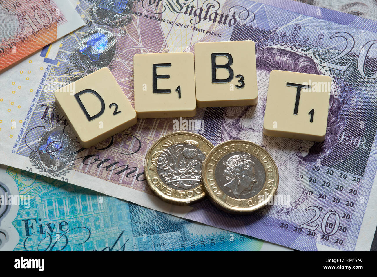Lettere di scrabble debito controllo ortografico con nuove sterline inglesi (GBP) £20, £10, £5 note e la nuova British pound monete. Foto Stock