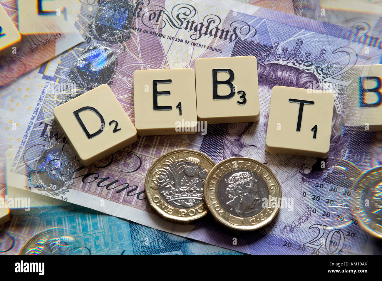 Lettere di scrabble debito controllo ortografico con nuove sterline inglesi (GBP) £20, £10, £5 note e la nuova British pound monete. Foto Stock