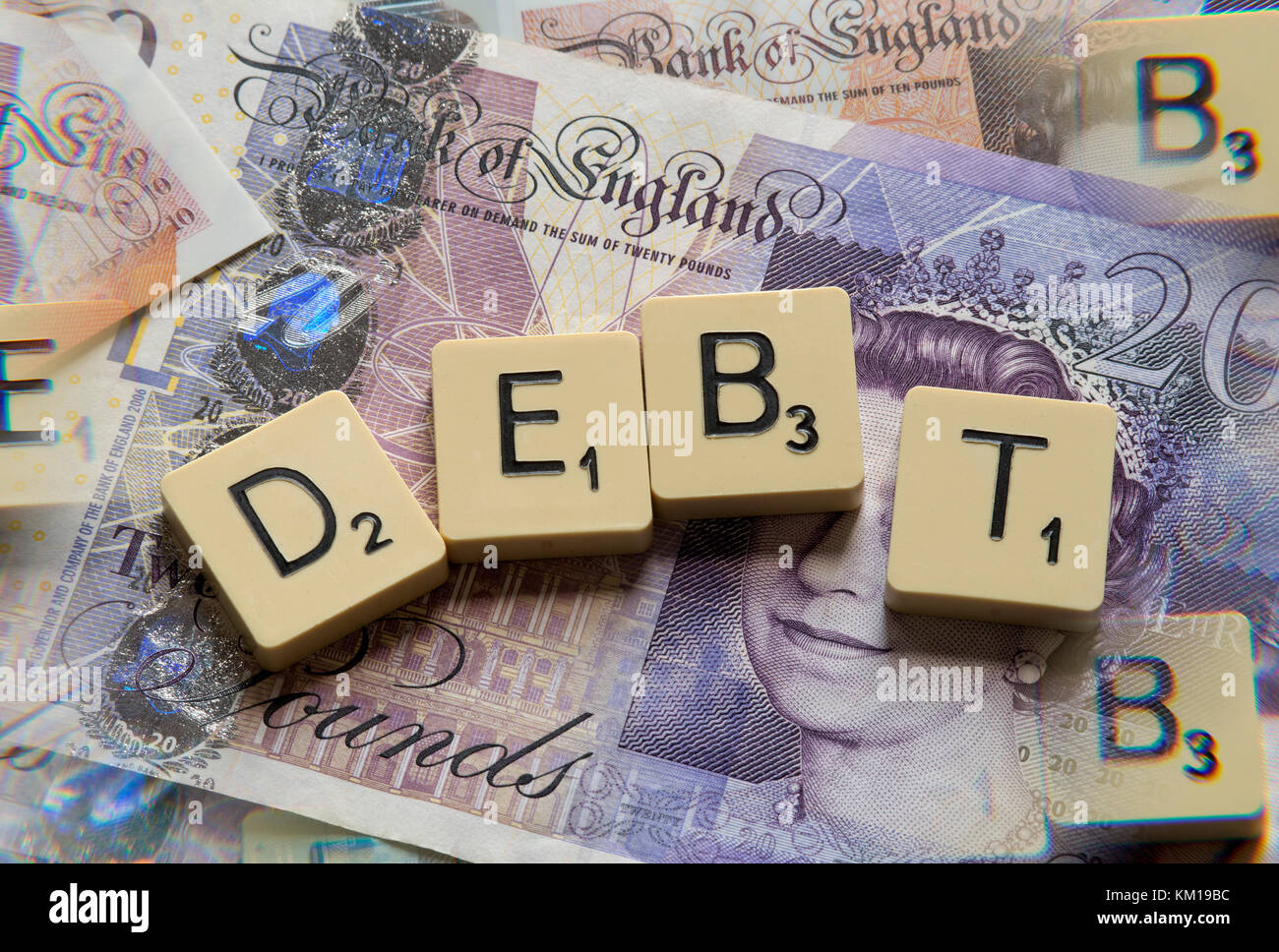 Lettere di scrabble debito controllo ortografico con nuove sterline inglesi (GBP) £20, £10, £5 note e la nuova British pound monete. Foto Stock