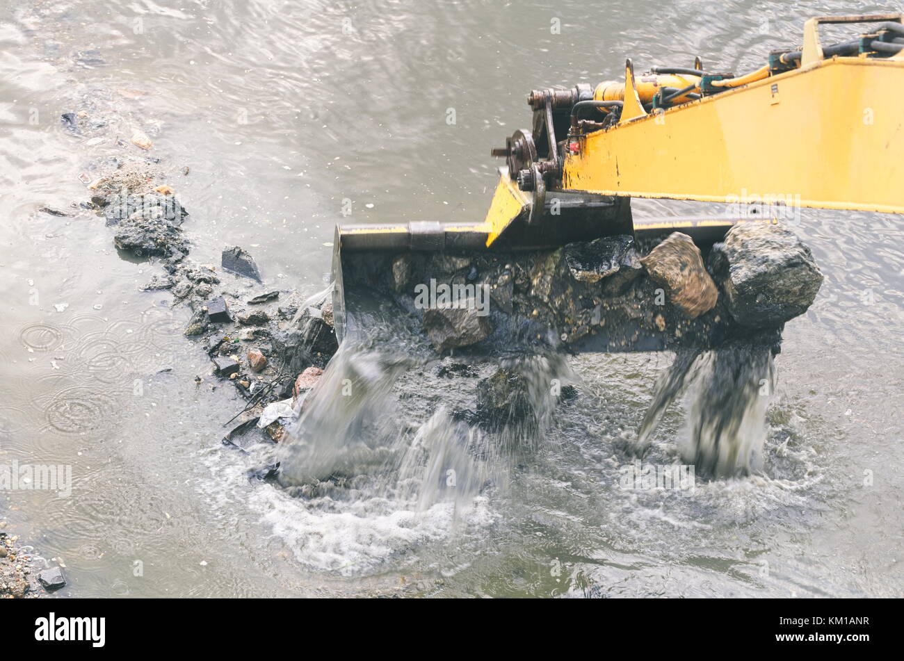 Escavatore giallo pulisce il letto del fiume closeup Foto Stock