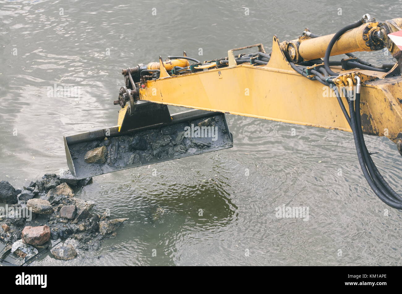 Escavatore giallo pulisce il letto del fiume closeup Foto Stock