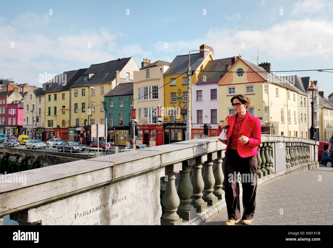 La città di Cork in Irlanda young business woman attraversando il Parlamento ponte sul fiume Lee con vecchi magazzini su Georges Quay dietro. Foto Stock