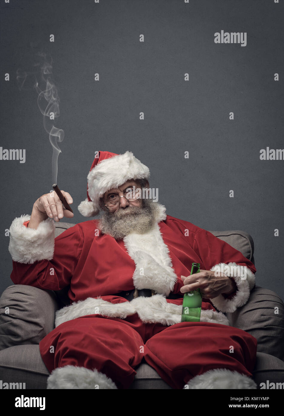 Bad santa celebra il Natale a casa da solo, egli sta fumando un sigaro e bere birra Foto Stock