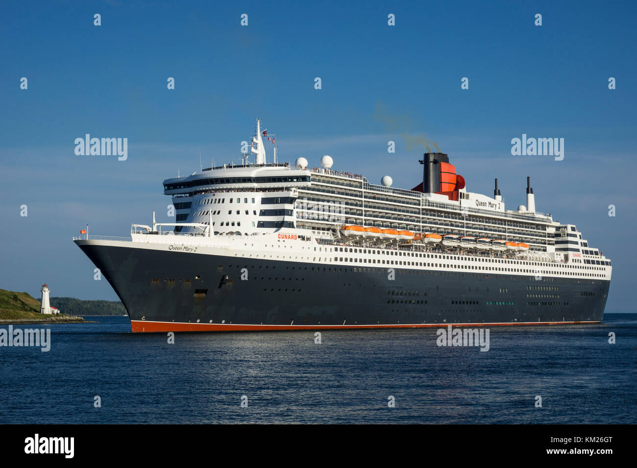 Queen Mary II passa il Georges Island Lighthouse nel porto di Halifax, Nova Scotia, Canada. Foto Stock