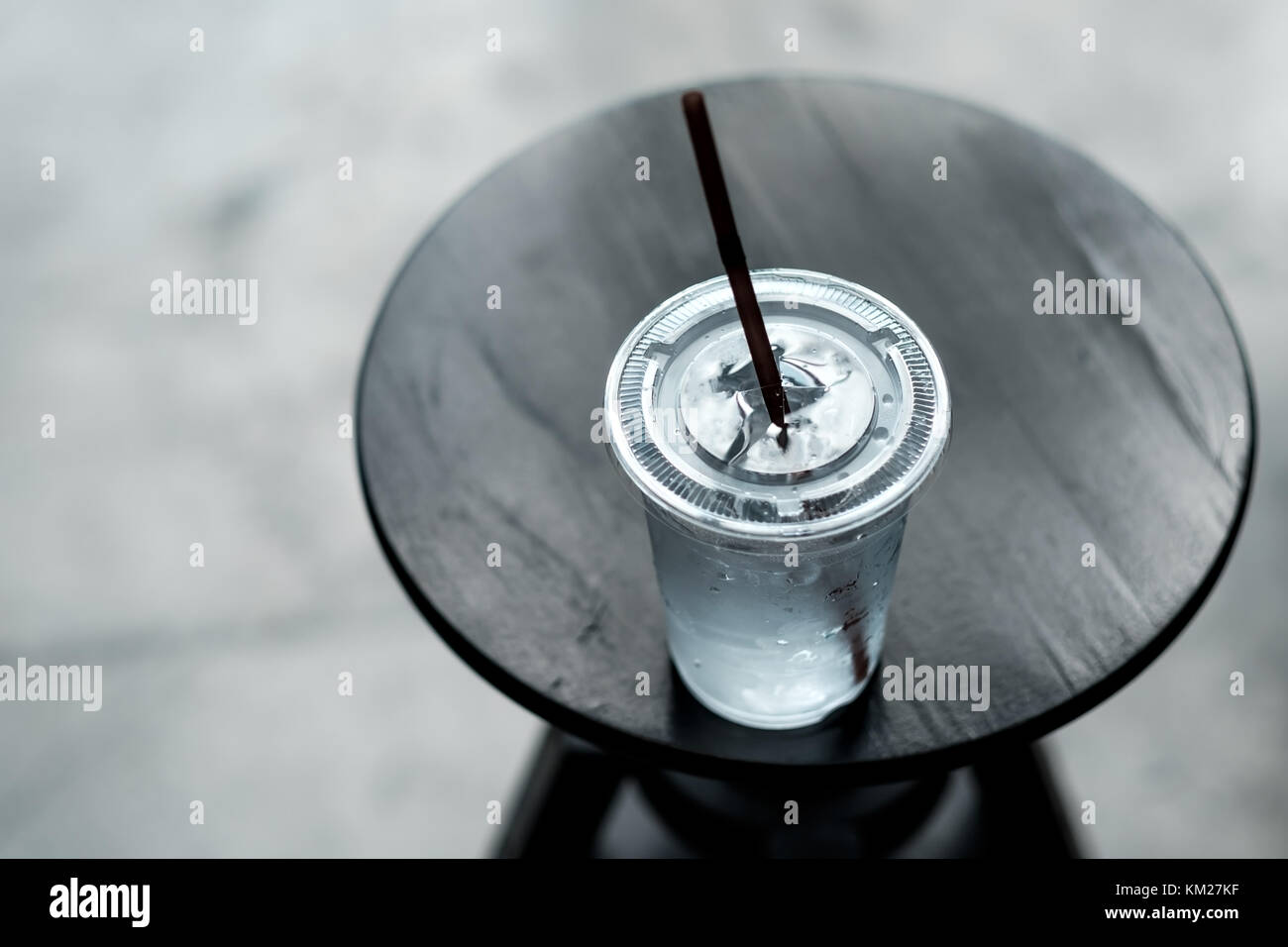 Una plastica lass di acqua fredda su un piccolo tavolo in legno Foto Stock