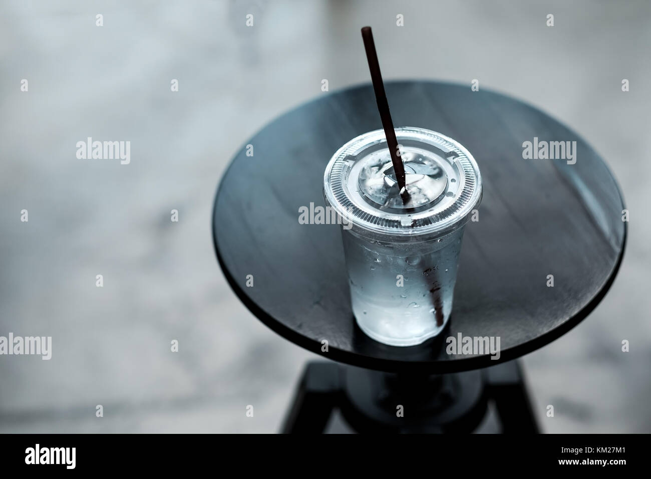 Una plastica lass di acqua fredda su un piccolo tavolo in legno Foto Stock