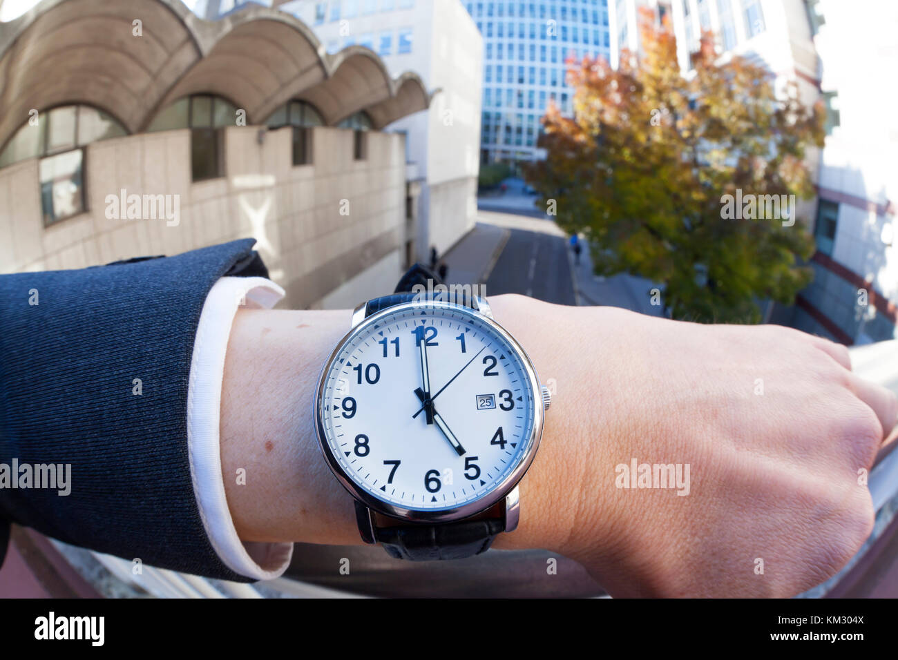 Close up di un uomo caucasico indossando un orologio da polso che mostra il tempo 5:00 Foto Stock