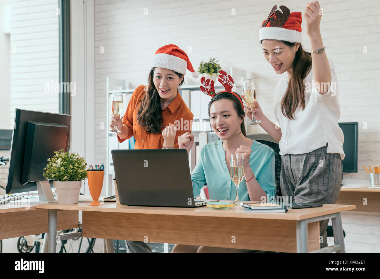 Un gruppo di giovani business group di persone sono seduti in cappelli di Babbo Natale in ultimo giorno di lavoro e utilizzo di computer laptop. giovani creativi sono celebratin Foto Stock