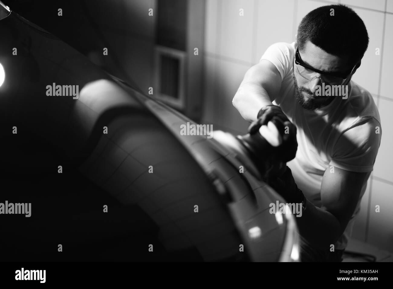 Dettagli auto - uomo con lucidatrice orbitale nel negozio di riparazioni auto. Il fuoco selettivo. Foto Stock