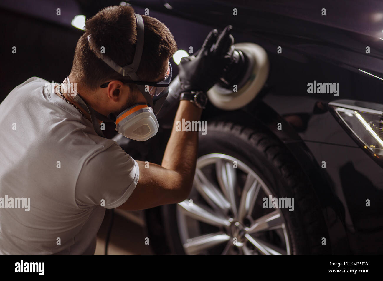 Dettagli auto - uomo con lucidatrice orbitale nel negozio di riparazioni auto. Il fuoco selettivo. Foto Stock