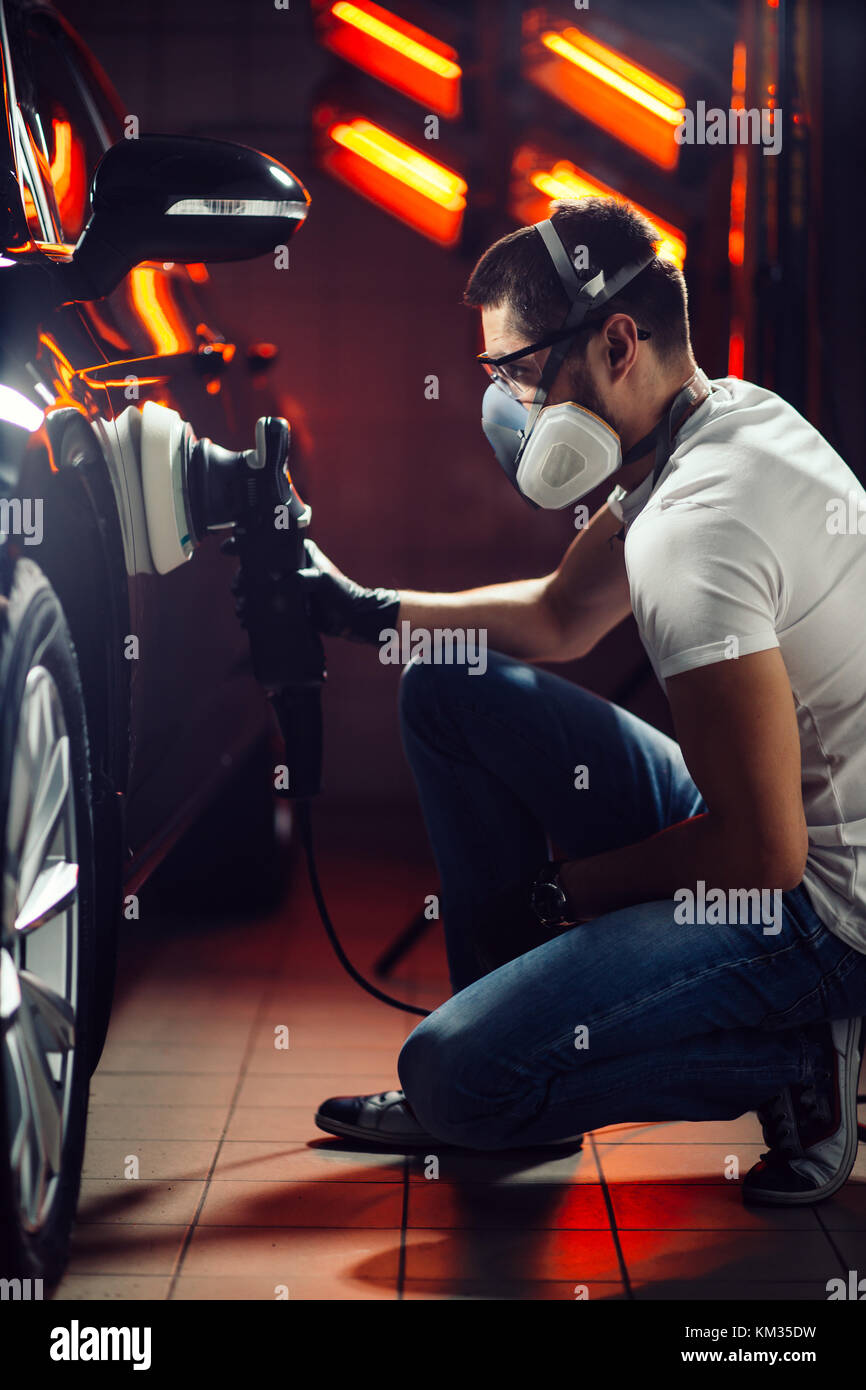 Dettagli auto - uomo con lucidatrice orbitale nel negozio di riparazioni auto. Il fuoco selettivo. Foto Stock