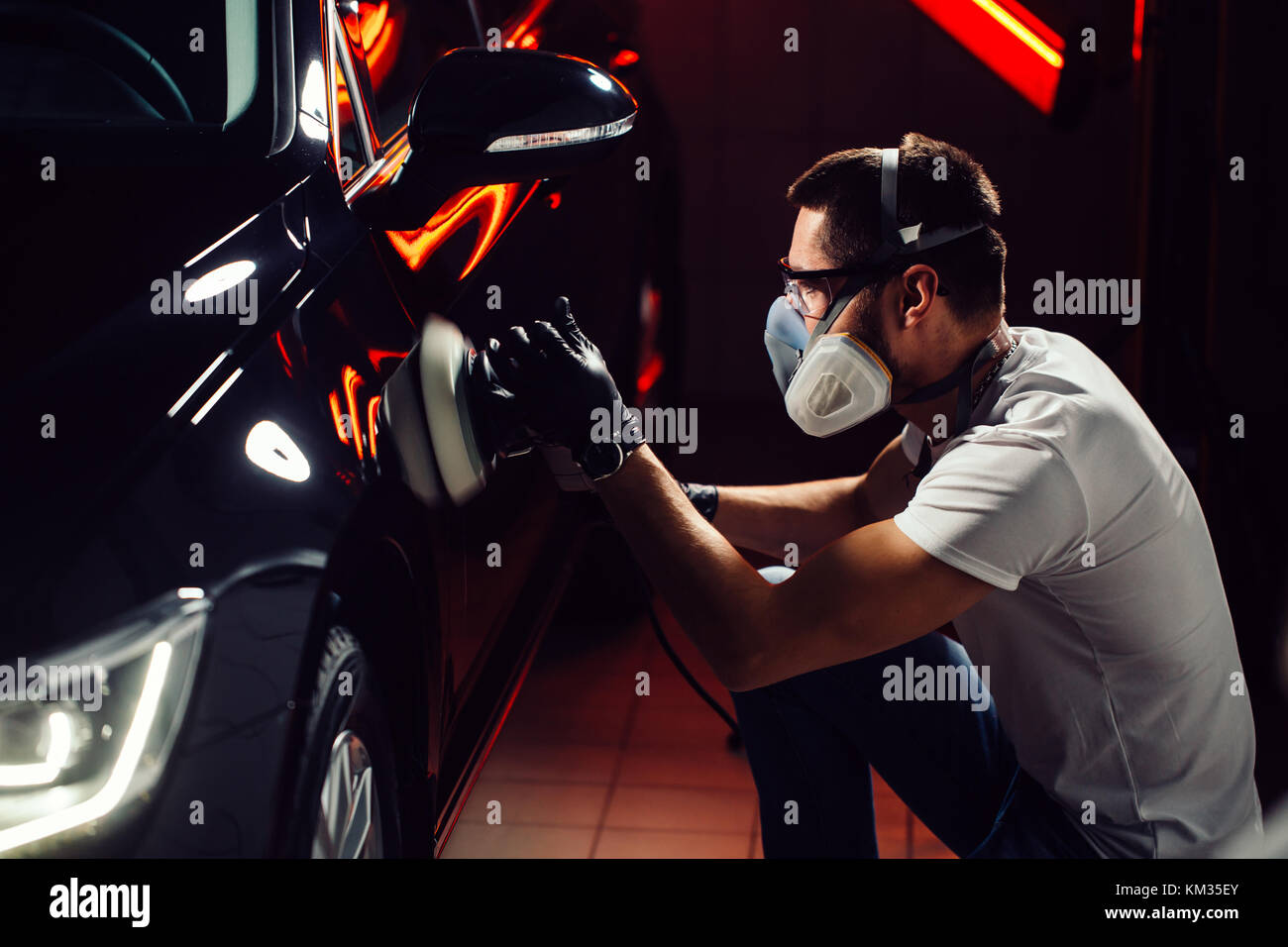 Dettagli auto - uomo con lucidatrice orbitale nel negozio di riparazioni auto. Il fuoco selettivo. Foto Stock