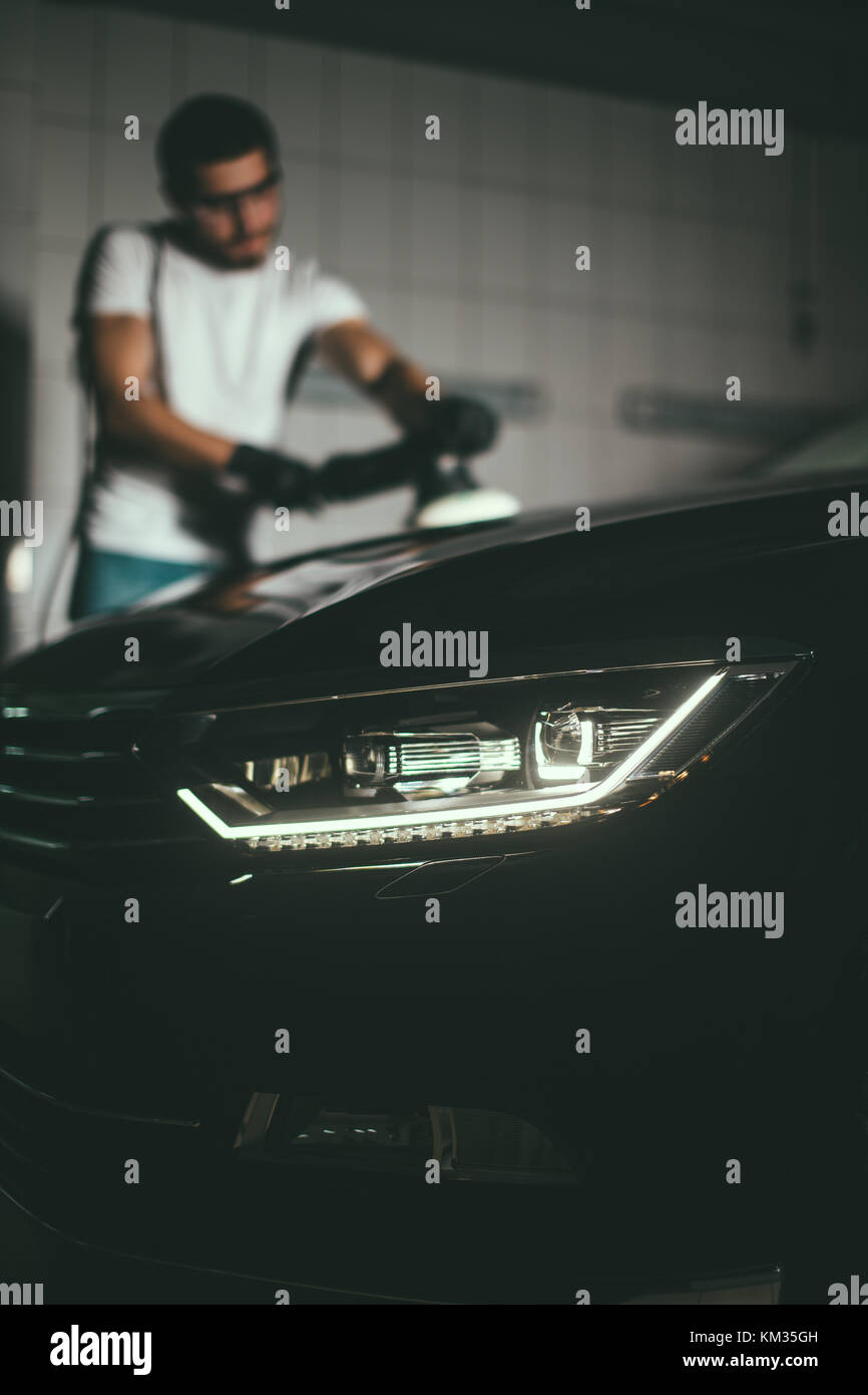 Dettagli auto - uomo con lucidatrice orbitale nel negozio di riparazioni auto. Il fuoco selettivo. Foto Stock