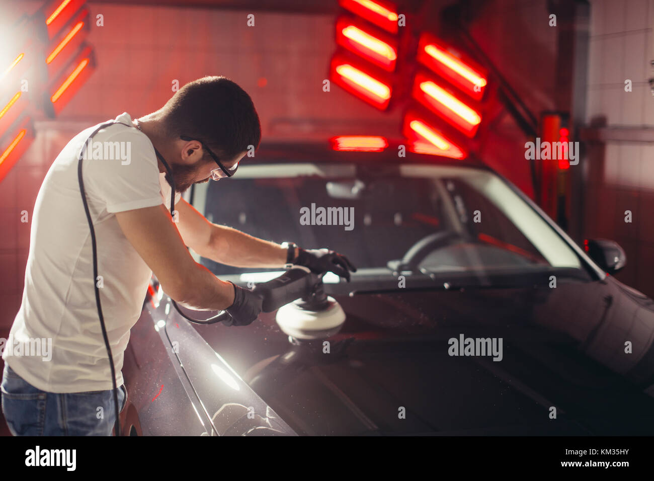 Dettagli auto - uomo con lucidatrice orbitale nel negozio di riparazioni auto. Il fuoco selettivo. Foto Stock