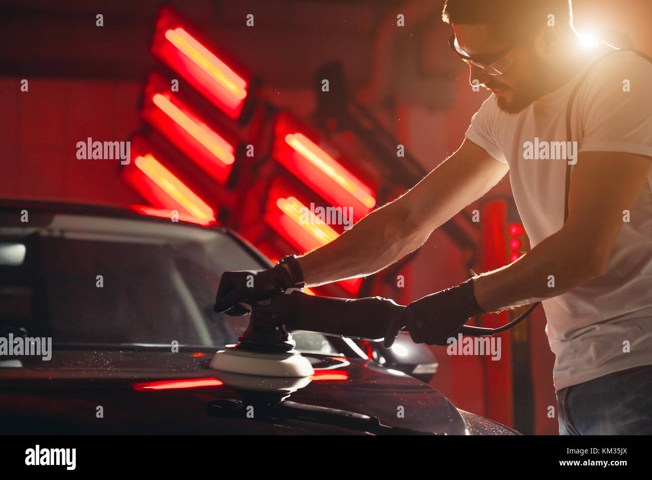 Dettagli auto - uomo con lucidatrice orbitale nel negozio di riparazioni auto. Il fuoco selettivo. Foto Stock