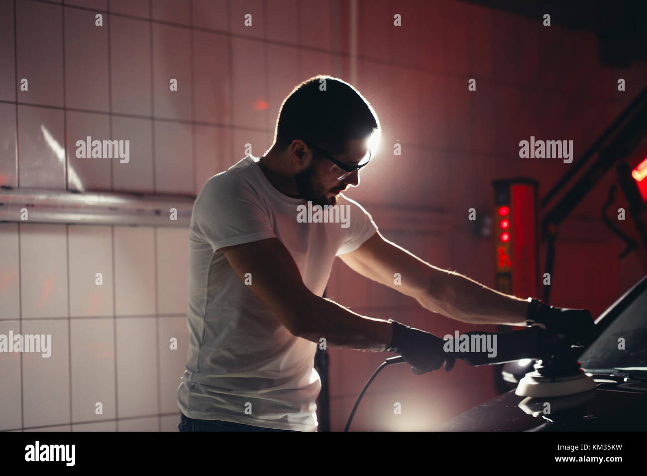 Dettagli auto - uomo con lucidatrice orbitale nel negozio di riparazioni auto. Il fuoco selettivo. Foto Stock