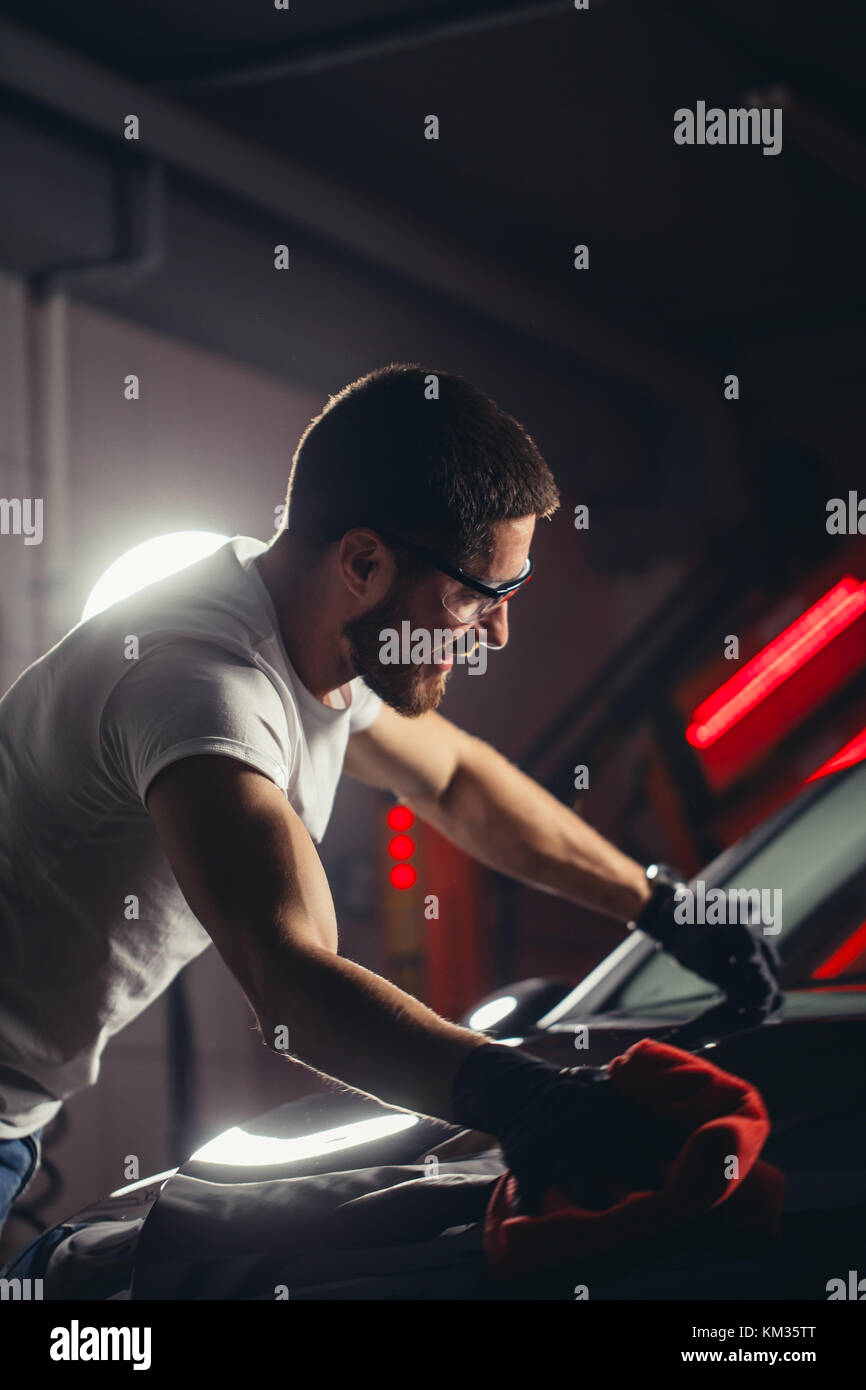 Dettagli auto - l'uomo detiene la microfibra in mano e leviga la vettura Foto Stock