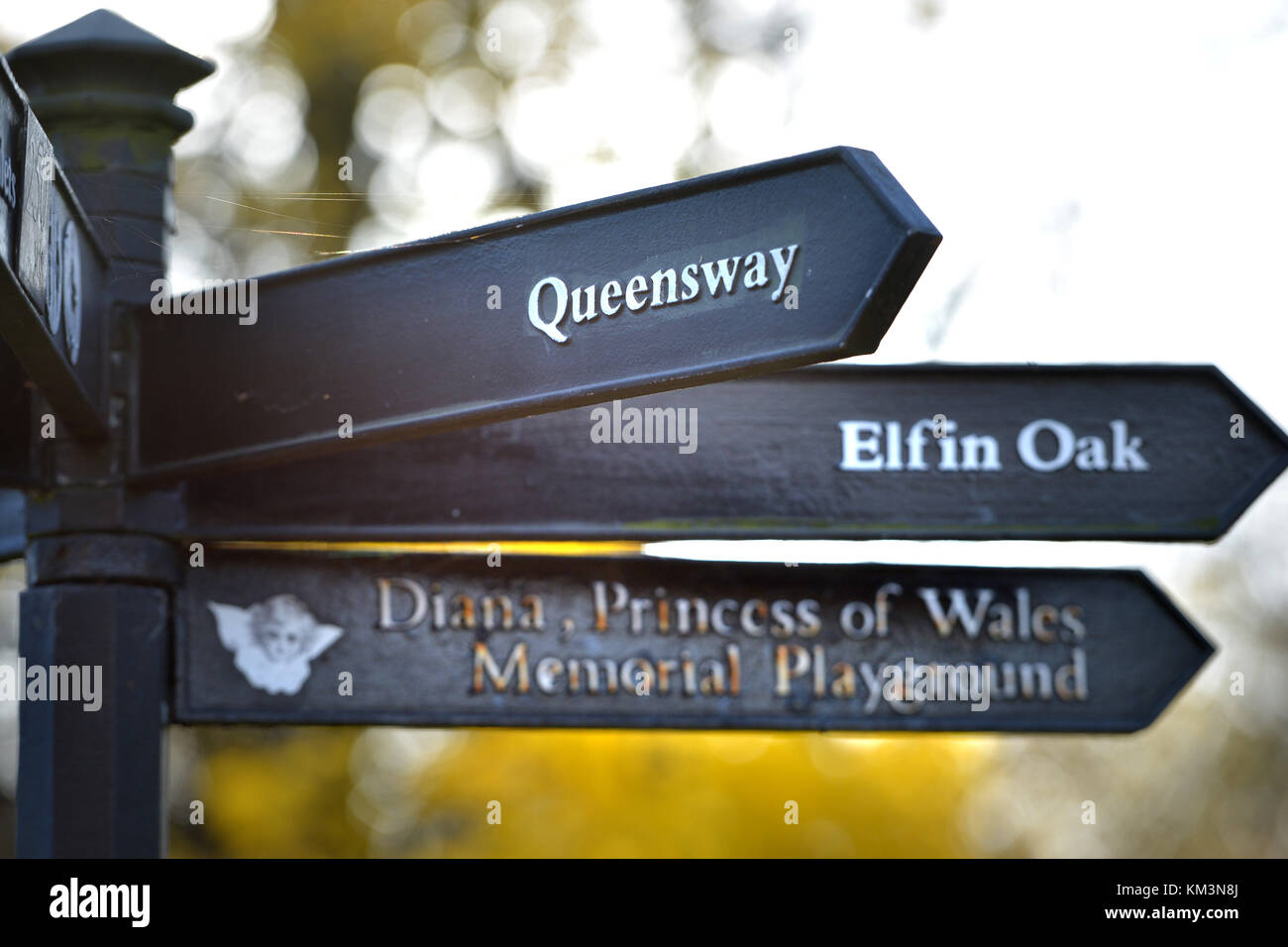 Segno posto in giardini di Kensington, London, mostrando Foliatile Oak, Queensway e il Princess Diana Memorial parco giochi Foto Stock