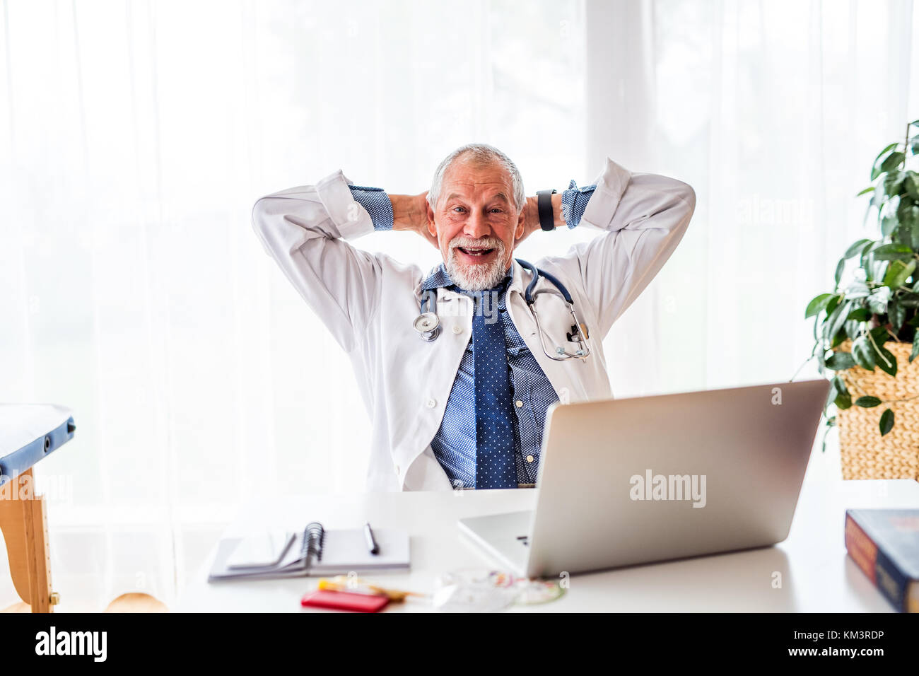 Senior medico con computer portatile presso la scrivania in ufficio. Foto Stock