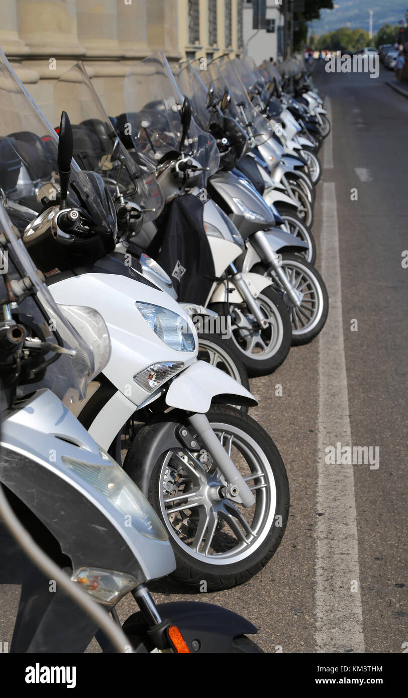 Firenze, FI, Italia - 21 agosto 2015: molti ciclomotori scooter e moto parcheggiate lungo la strada trafficata Foto Stock