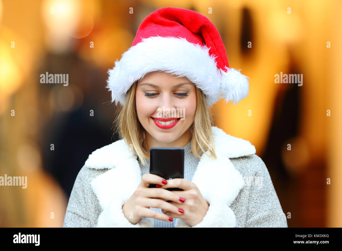 Vista frontale il ritratto di una ragazza felice invio di smart phone messaggi in vacanze di Natale sulla strada Foto Stock