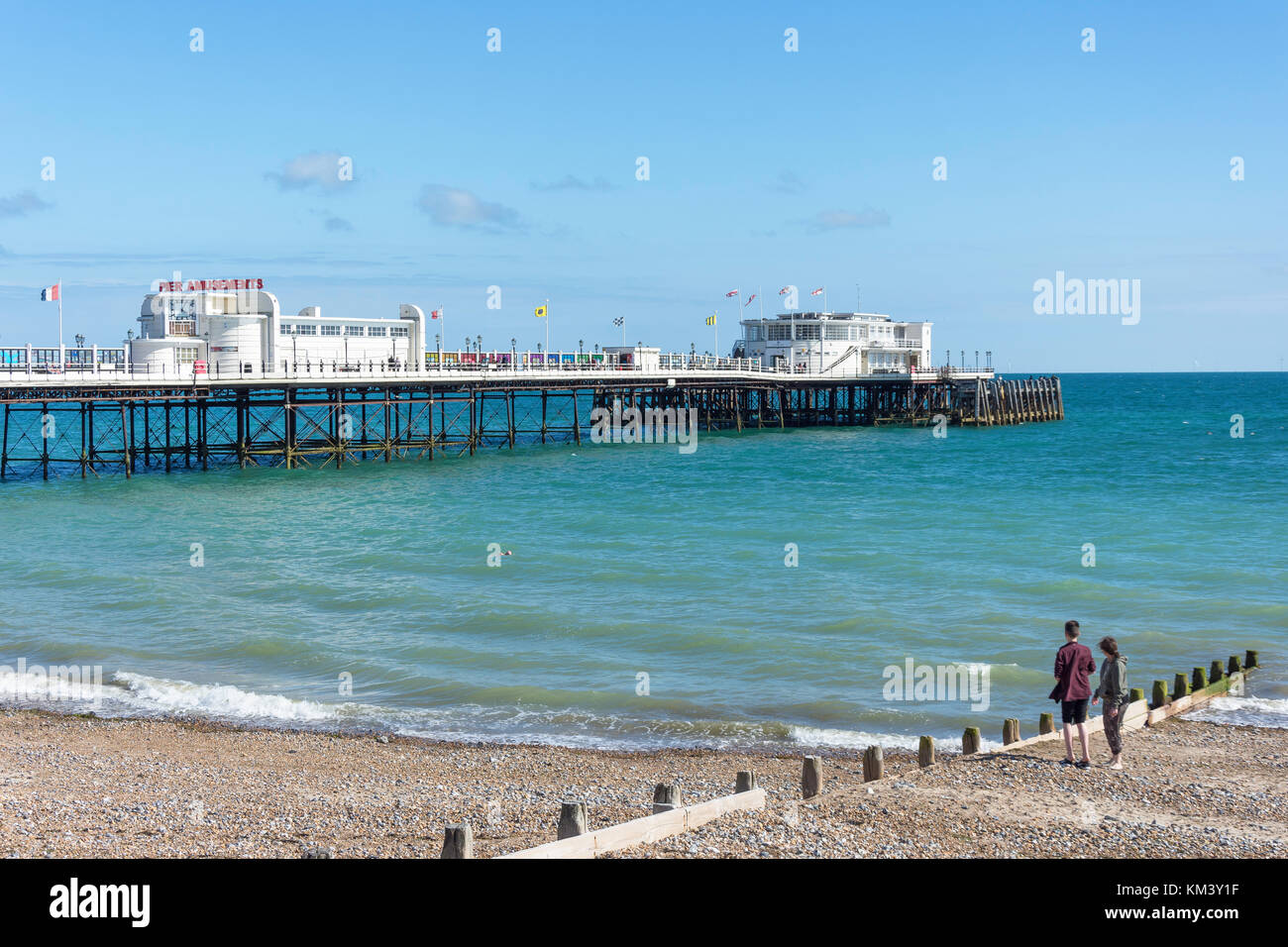 Coppia giovane sulla spiaggia e Worthing Pier, Worthing, West Sussex, in Inghilterra, Regno Unito Foto Stock