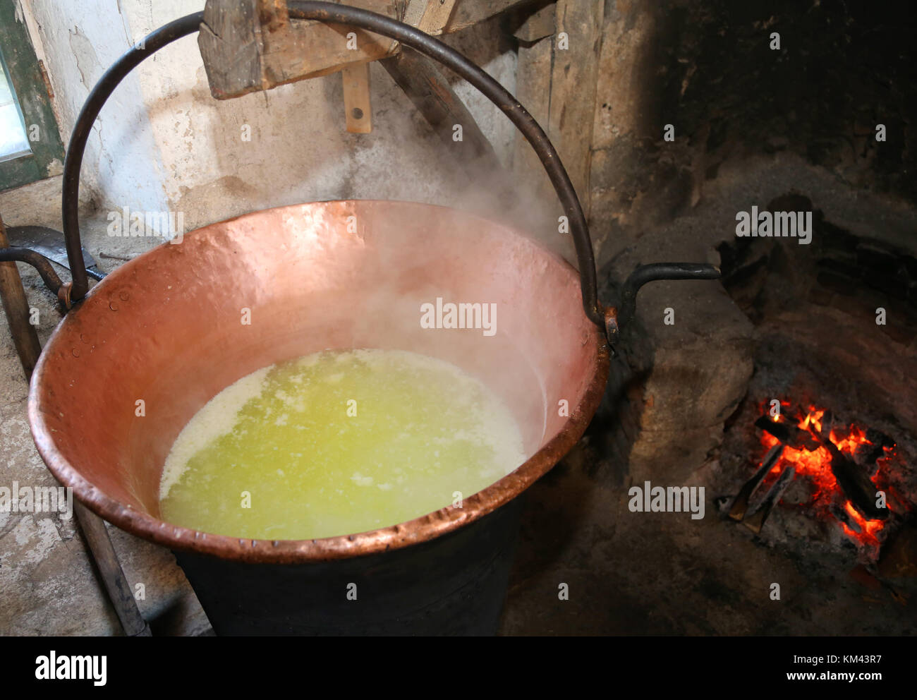 Grande paiolo di rame per riscaldare il siero di latte per la produzione di  formaggio in una latteria all'interno dello stallo in montagna e di fuoco  Foto stock - Alamy