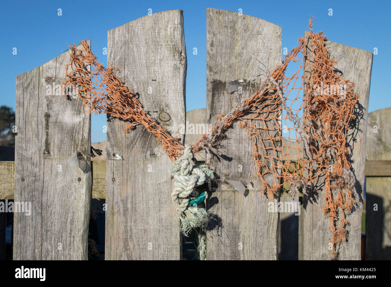 Una soleggiata giornata autunnale che mostra una recinzione di legno con alcune reti a strati e una corda drappeggiata. Villaggio di Carsethorn, Scozia. Foto Stock