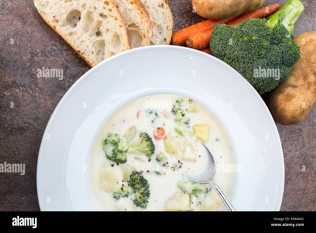 Una grande ciotola bianco casereccio broccoli cremosa ,potato ,formaggio e pancetta minestra con un rustico di crosta di pane e verdure Foto Stock