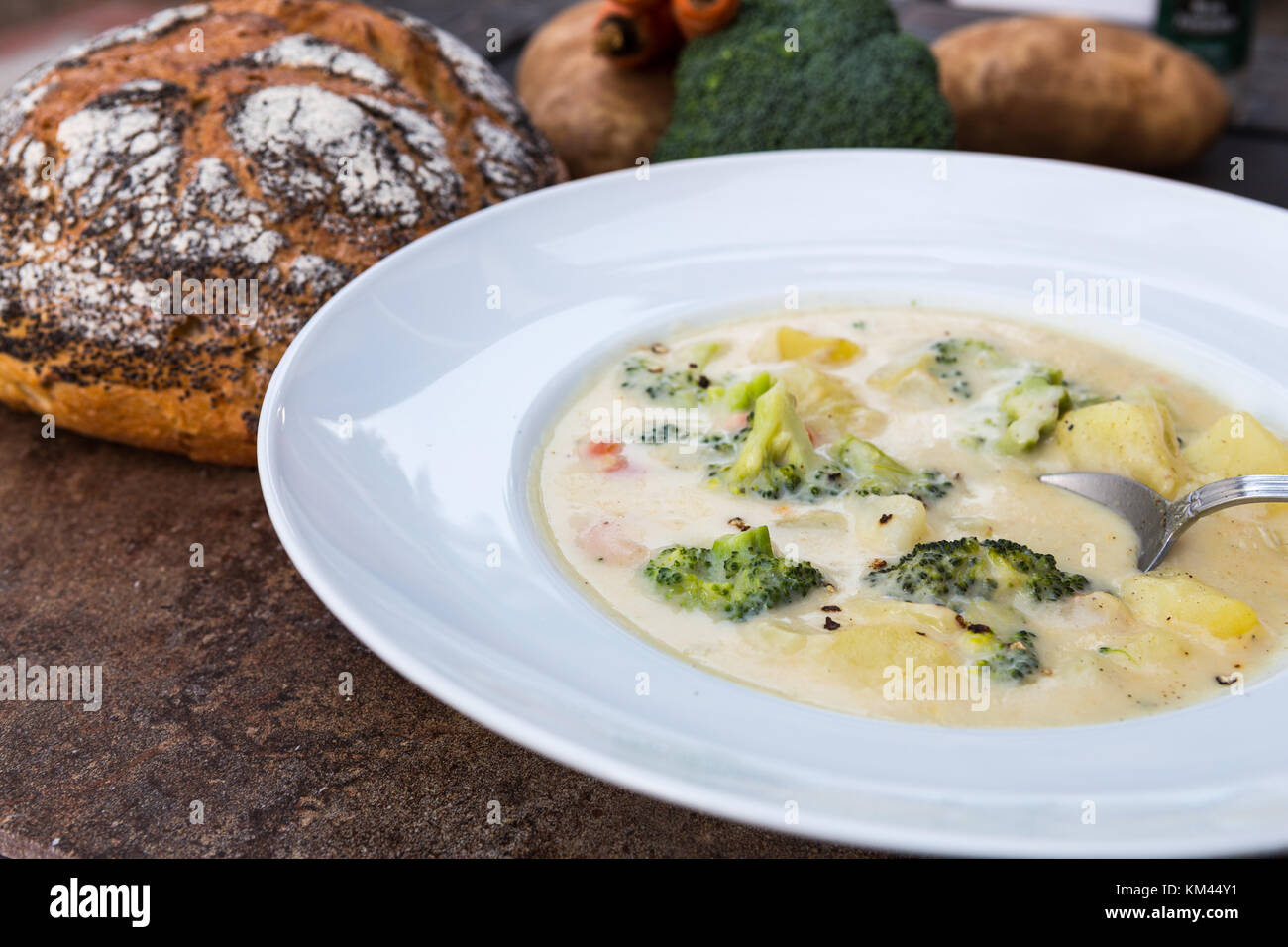 Una grande ciotola bianco casereccio broccoli cremosa ,potato ,formaggio e pancetta minestra con un rustico di crosta di pane e verdure Foto Stock