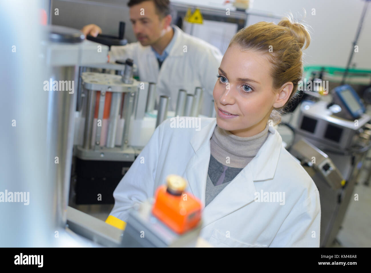 La donna a labcoat da macchine industriali Foto Stock
