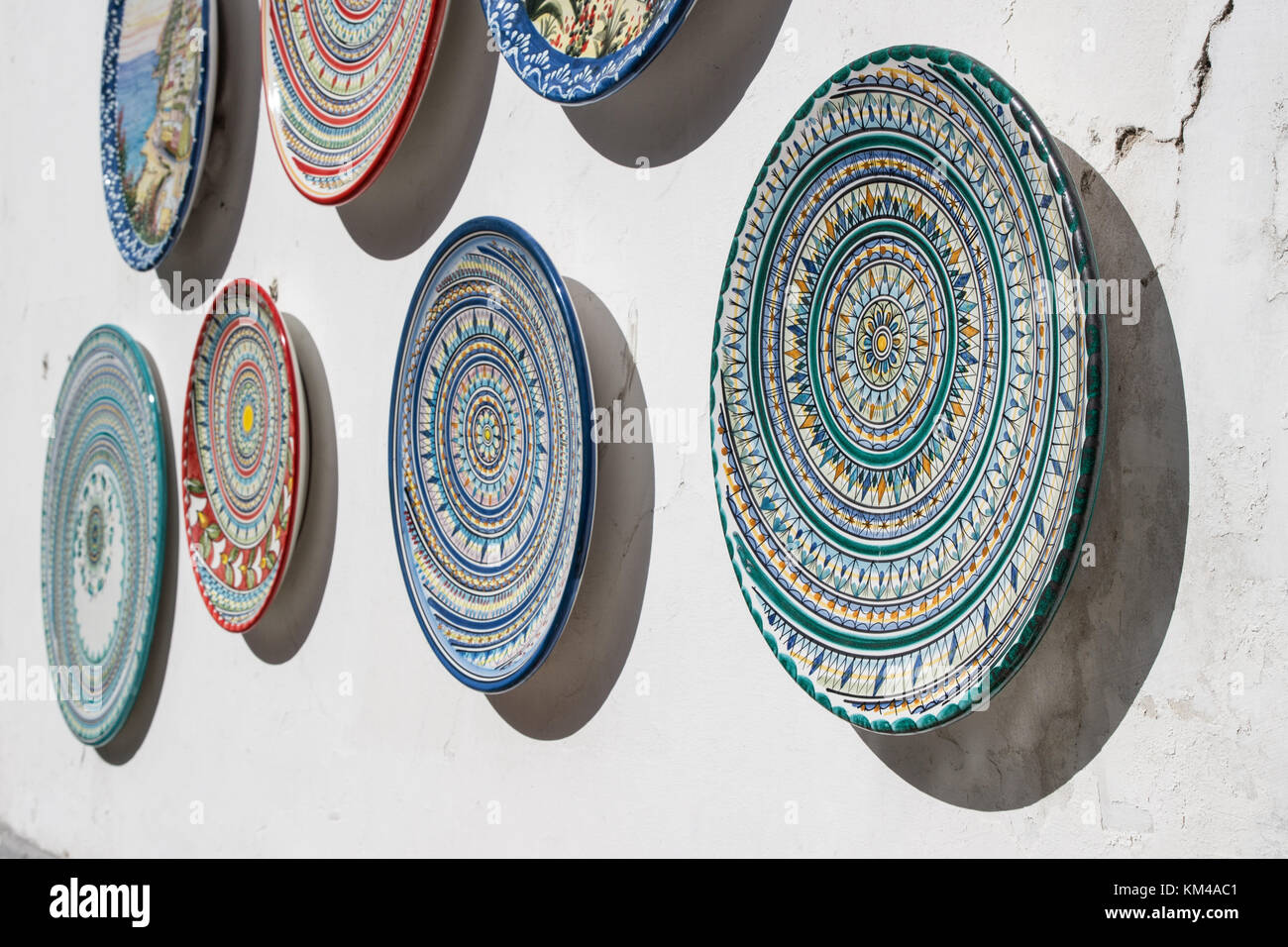 Varie ceramiche decorate piatti appeso per la vendita al di fuori di un negozio di souvenir a costiera amalfitana, Italia. Foto Stock
