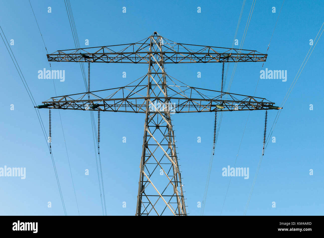 In prossimità della parte superiore di un valore di tensione alto traliccio di potenza isolati contro un cielo blu. Foto Stock