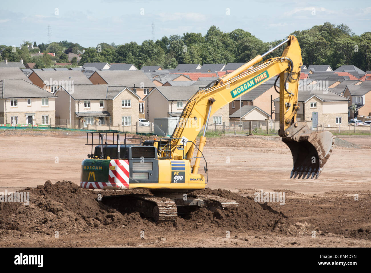 Costruzione casa su un sito brownfield in Bishopton, Scozia che mostra le nuove case, disboscata e scavatori prepara il terreno Foto Stock