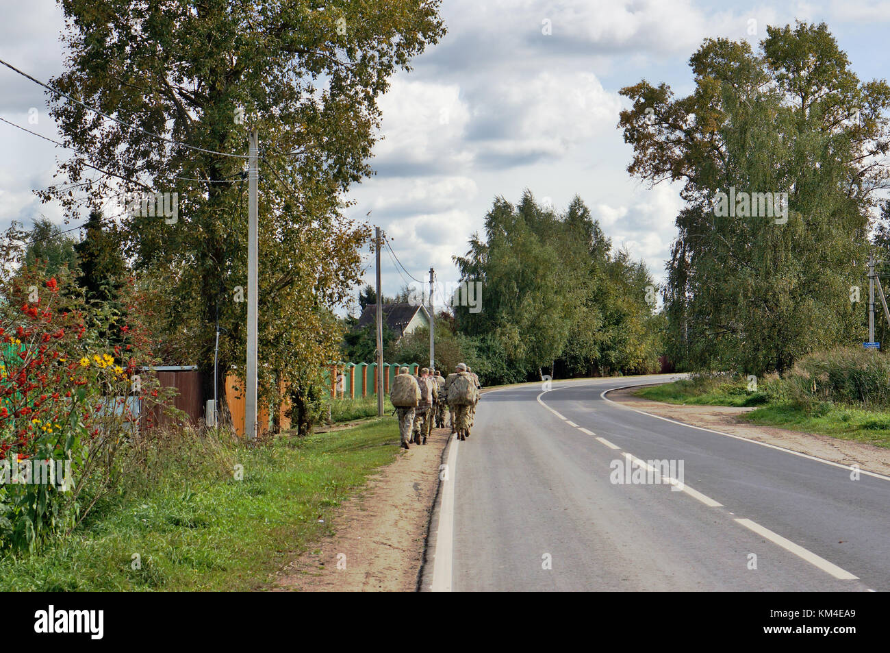 Soldati russi di forze speciali lasciare strada del villaggio per esercizi di campo. vista dal retro. nessuna persona riconoscibile o logo. autunno mili rurale Foto Stock