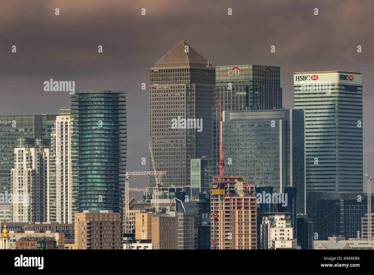 Le torri in vetro e acciaio di Canary Wharf con una nuova costruzione in corso sotto i cieli tempestosi da Greenwich Park, Londra, Regno Unito Foto Stock