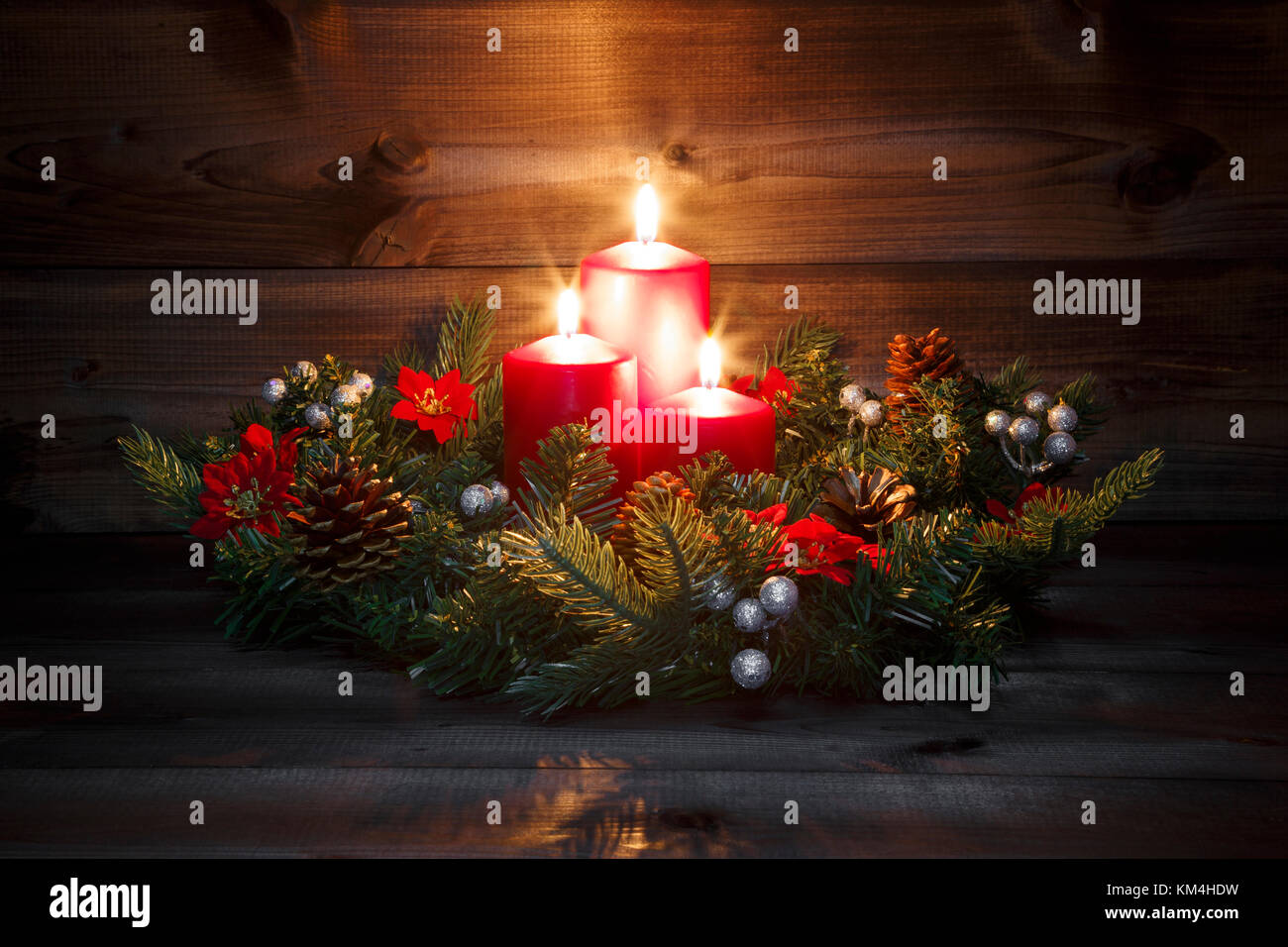 Terzo Avvento - decorato corona di Avvento con tre rossi candele accese su uno sfondo di legno con atmosfera festosa. Foto Stock