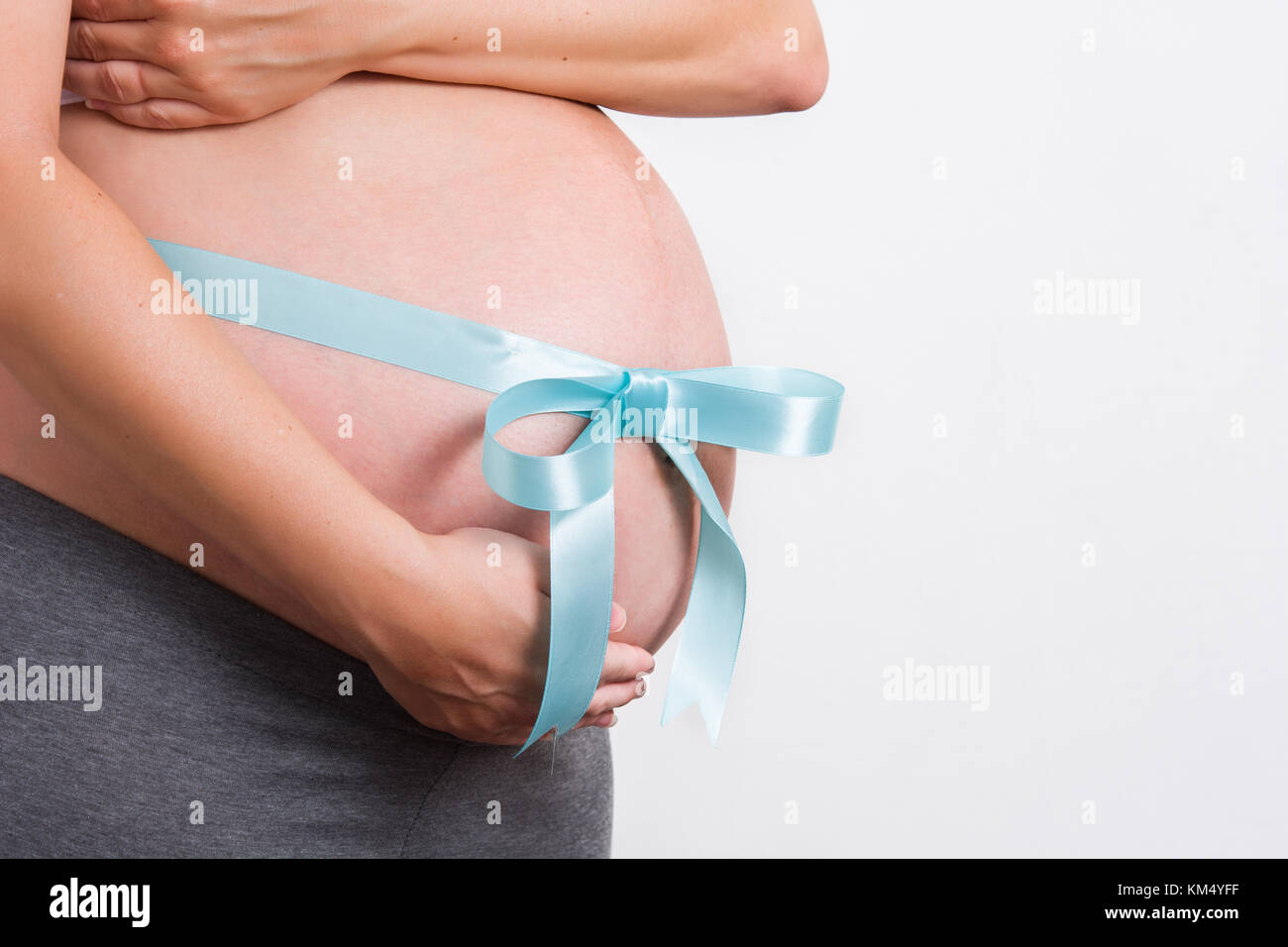 Donna incinta con nastro legato attorno al suo ventre Foto Stock