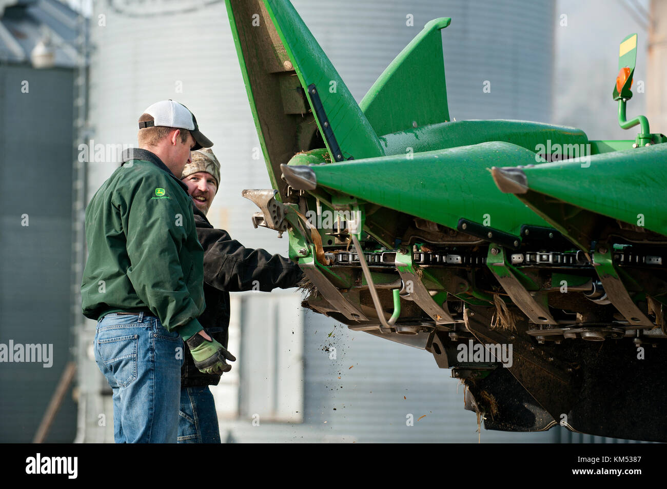 Agricoltore HELPER E PULIRE LA MIETITREBBIA JOHN DEERE prima di uscire per la raccolta di mais in UTICA, Minnesota. Foto Stock