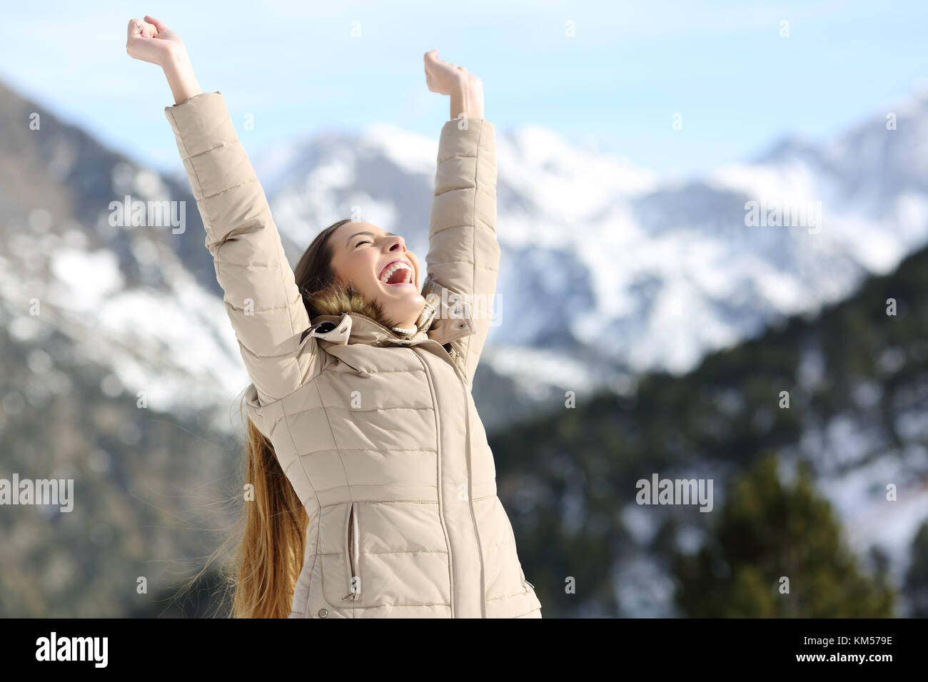 Excited donna i bracci di sollevamento per celebrare il successo nella montagna innevata in inverno Foto Stock