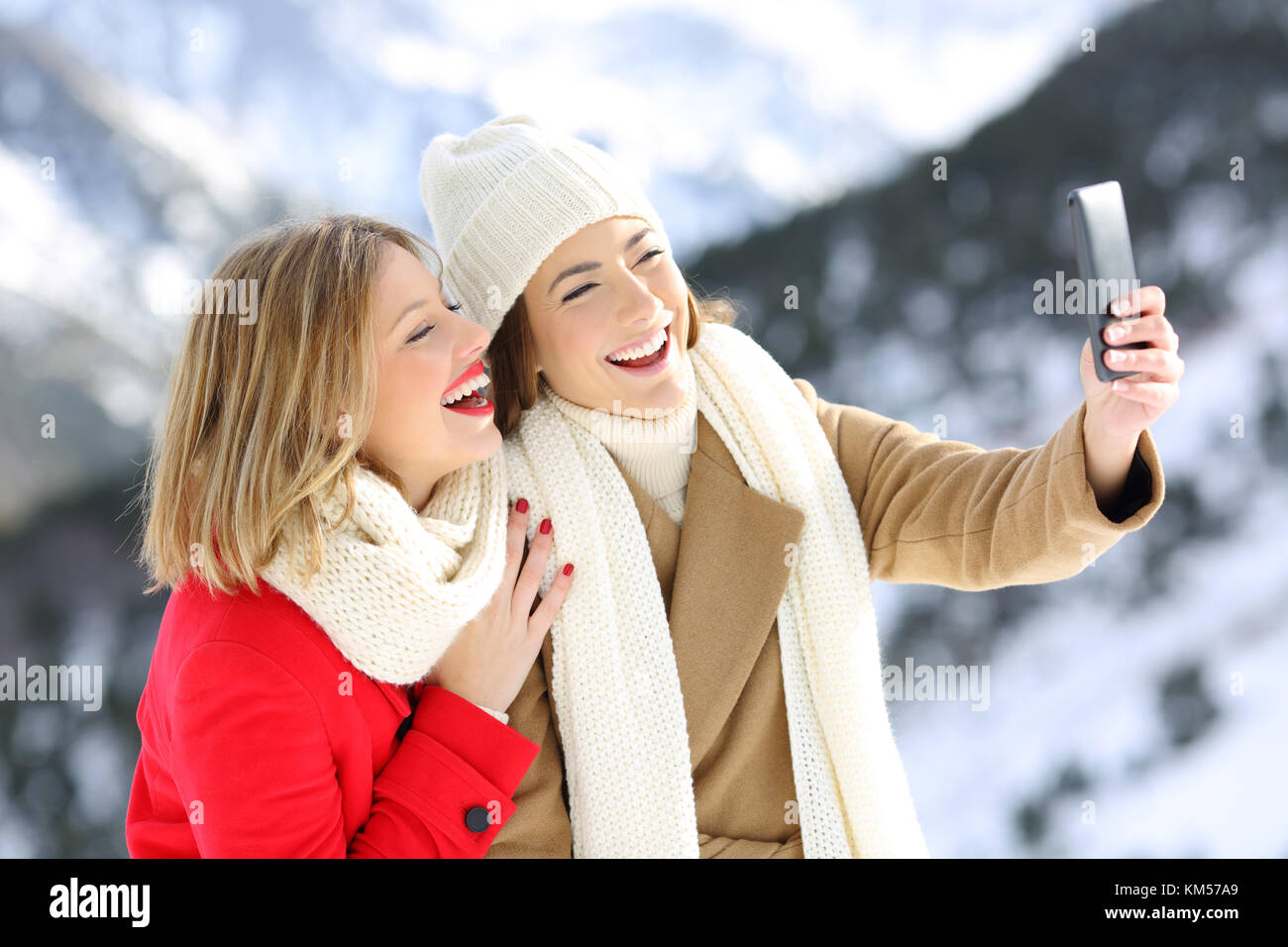 Due amici felice tenendo selfies in vacanza invernale con una montagna innevata in background Foto Stock